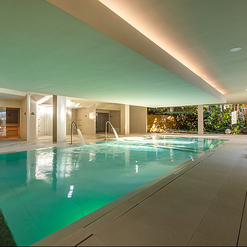 Piscina interior de hotel con tumbonas y spa, perfecta para tu Port Hotels: Corporativa.
