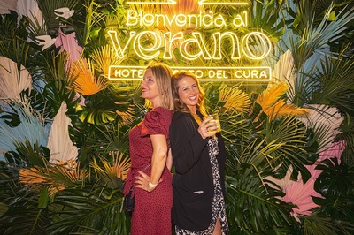 two women pose in front of a sign that says bienvenido al verano - 