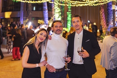 three people posing for a picture with one holding a glass of wine - 