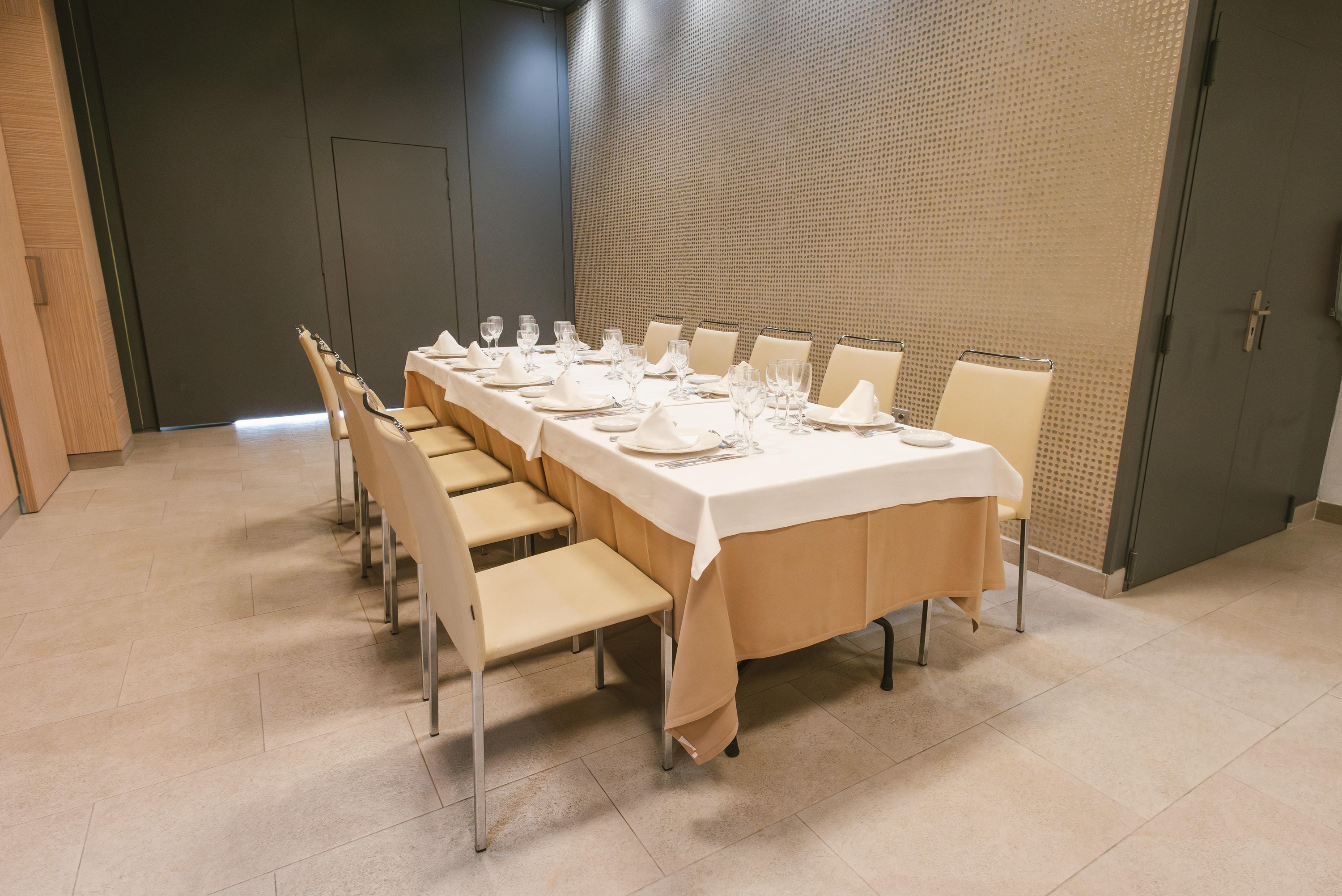 Elegant dining setup for a private event or meeting in a hotel, featuring a long table, chairs, and modern decor.