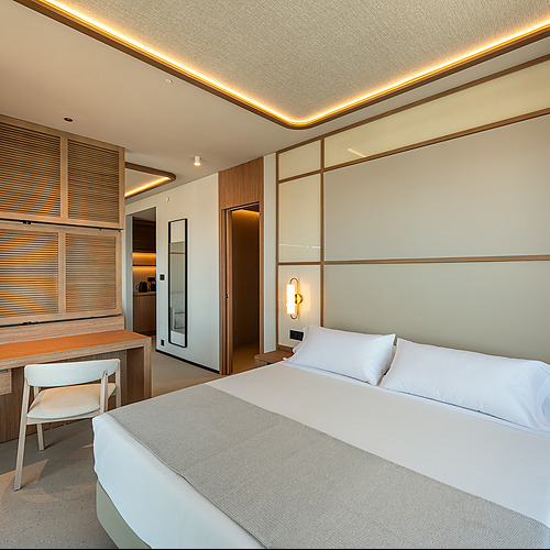 Habitación moderna con cama king, escritorio y armario de madera. Port Hotels: Corporativa