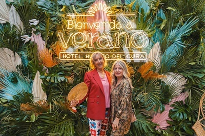 two women standing in front of a sign that says bienvenido al verano - 