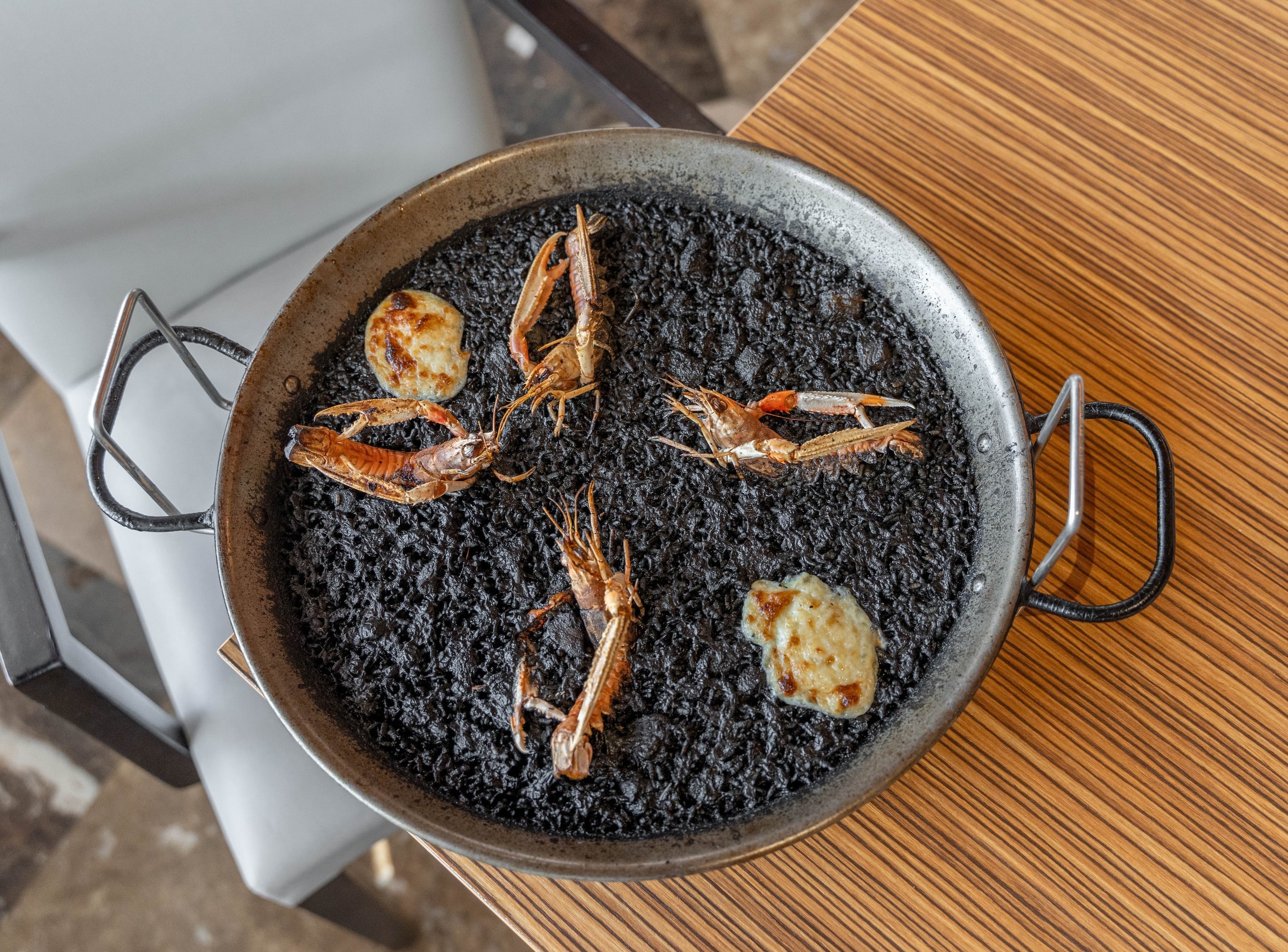 Black paella (arroz negro) with langoustines in a paella pan, served at a hotel restaurant.