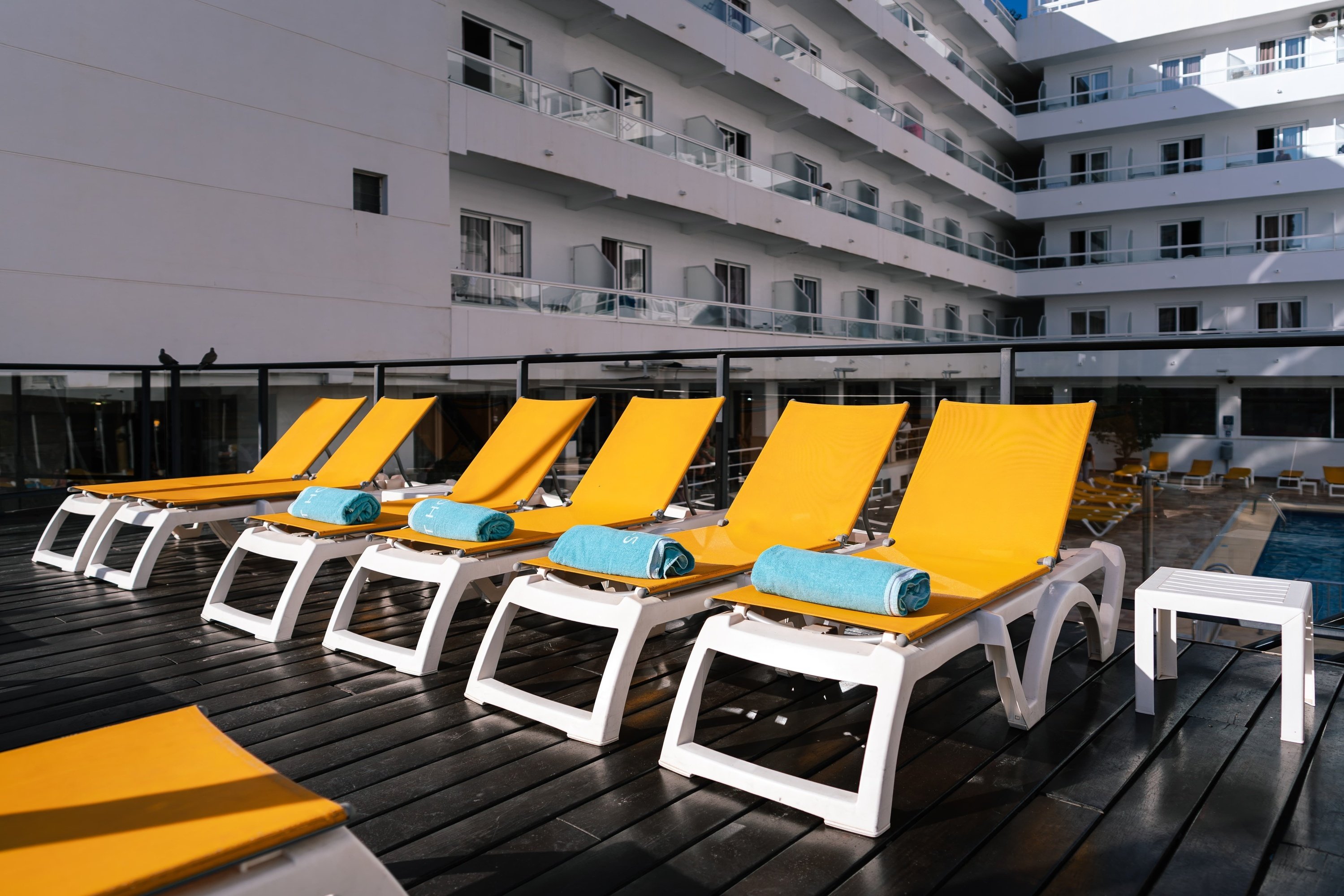 a row of yellow lounge chairs with blue towels on them