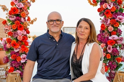 a man and woman are posing for a picture in front of flowers - 