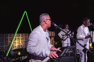 a man in a white jacket is playing a keyboard and singing into a microphone - 