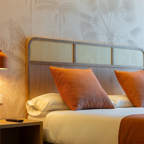 una cama con dos almohadas naranjas en una habitación de hotel