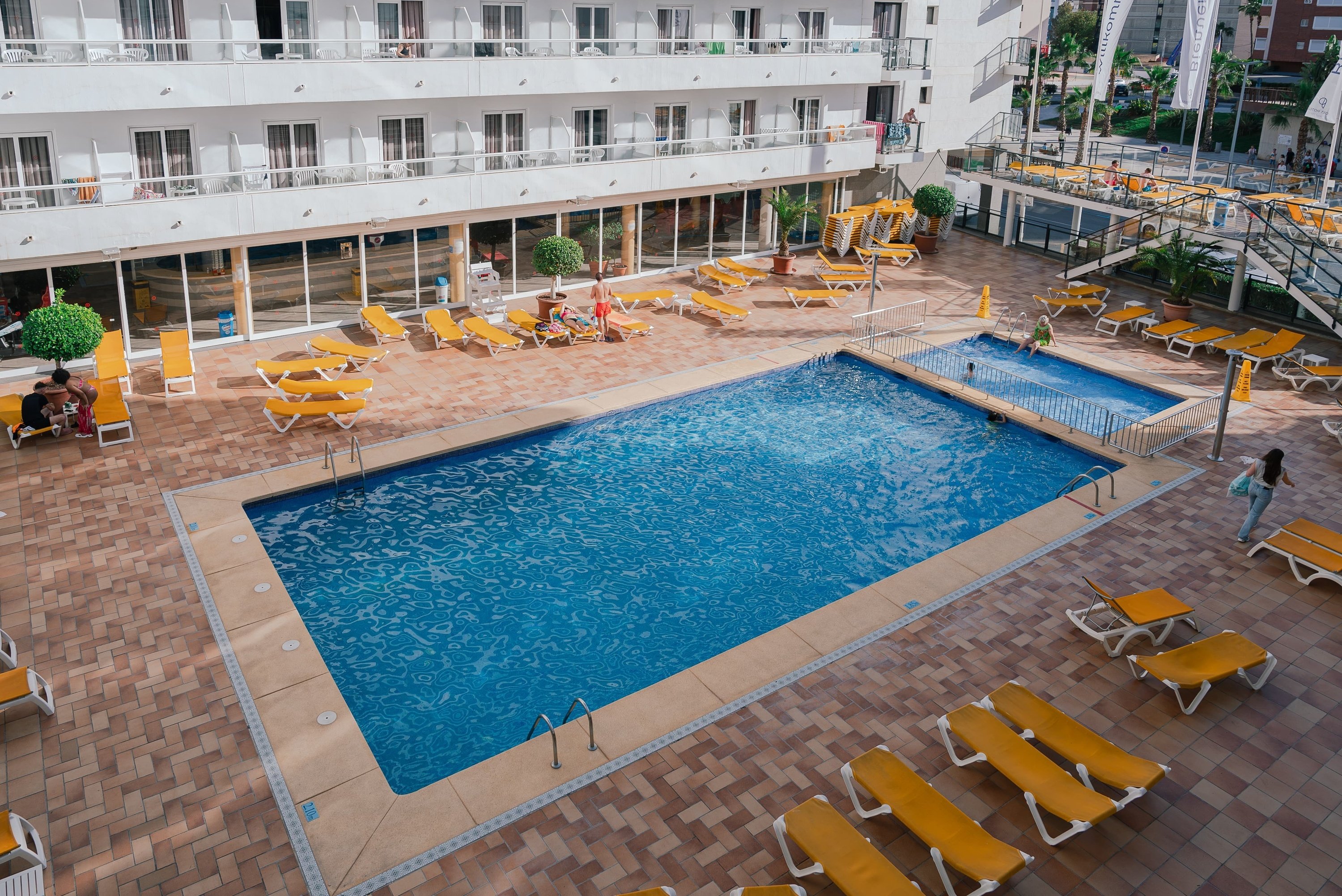 una piscina en un hotel con sillas amarillas alrededor