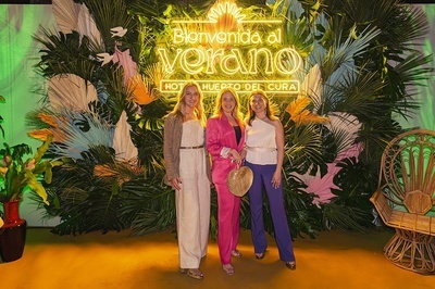 three women pose in front of a sign that says bienvenido al verano - 