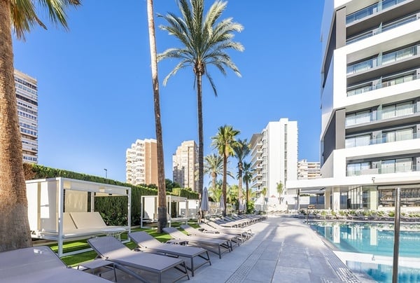 una piscina rodeada de sillas y sombrillas en un hotel