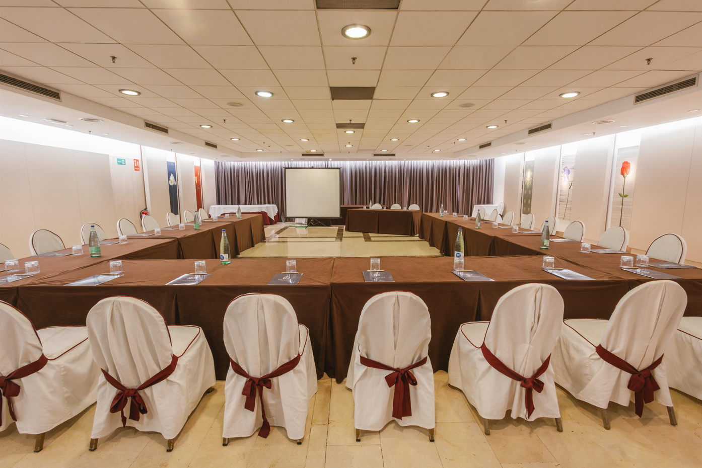 una sala de conferencias con mesas y sillas y una pantalla