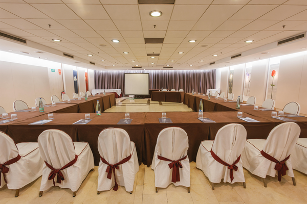 una sala de conferencias con mesas y sillas y una pantalla