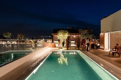 people are gathered around a large swimming pool at night - 