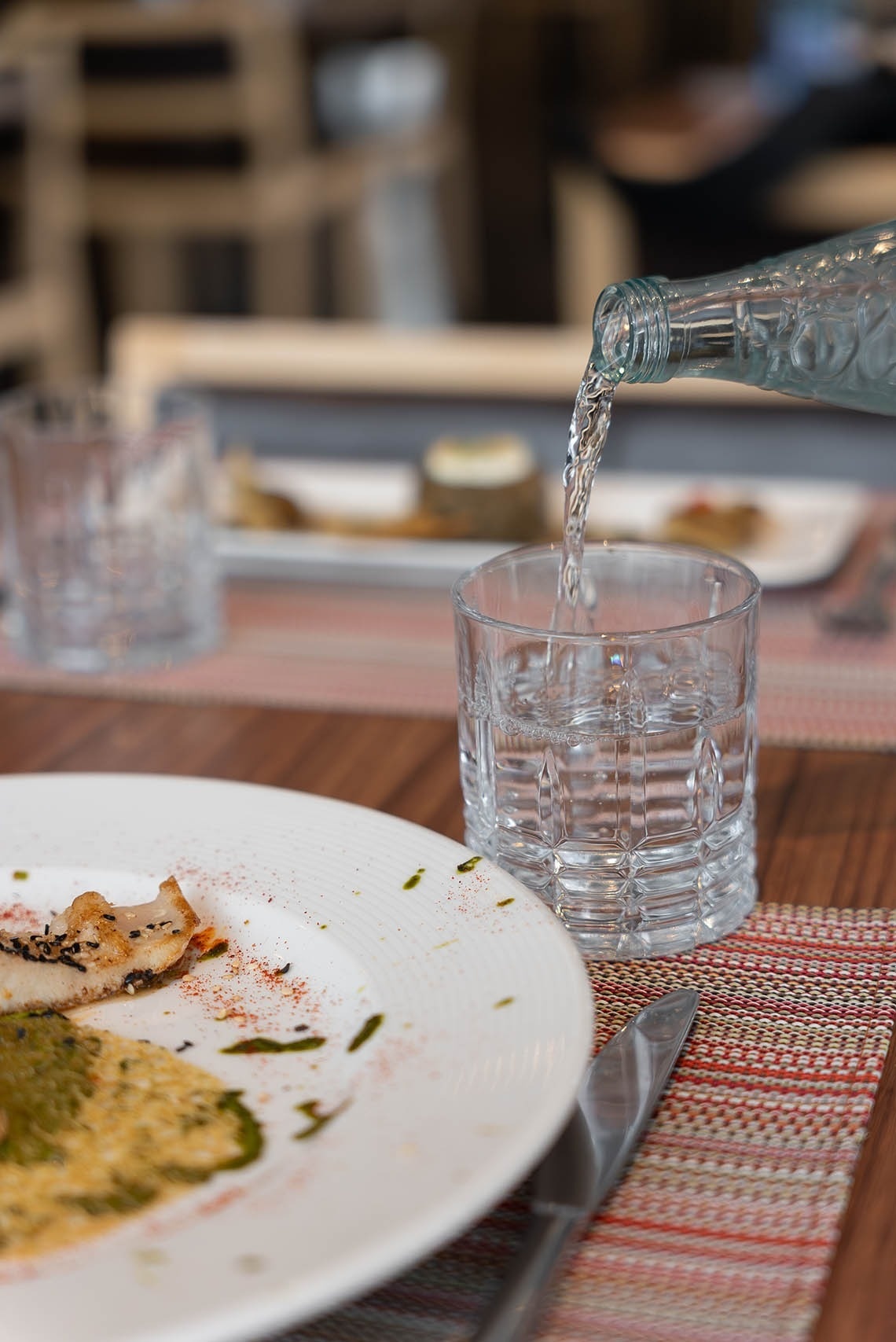 una botella de agua se vierte en un vaso sobre una mesa