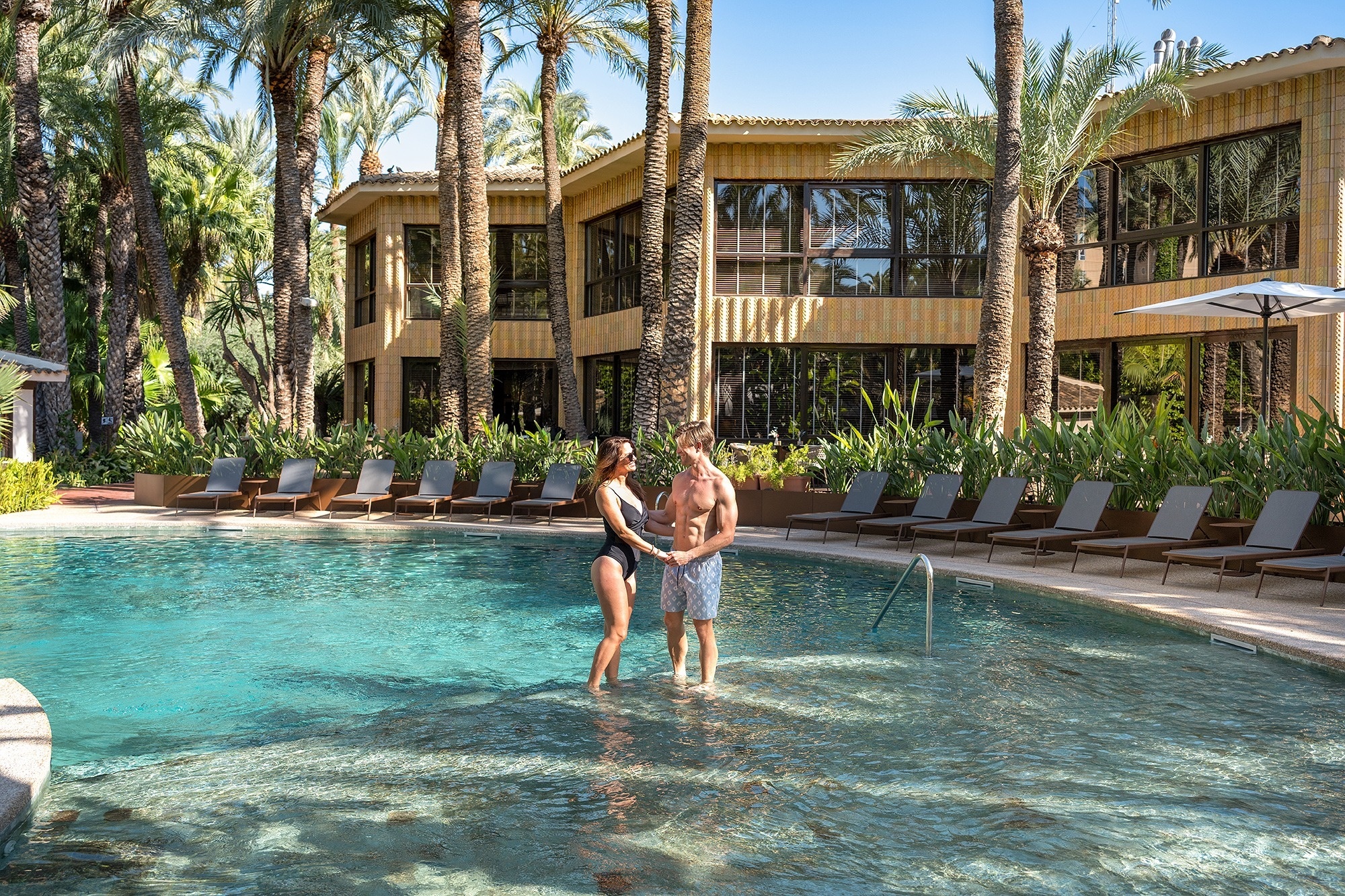 a man and a woman are standing in a swimming pool