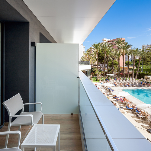 un balcón con dos sillas y una mesa frente a una piscina