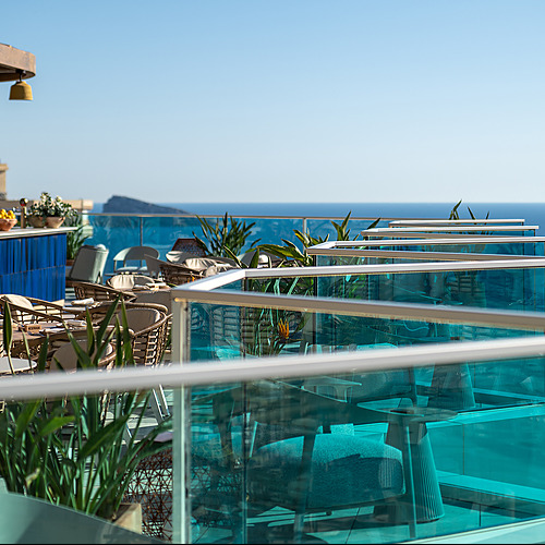 Terraza con vista al mar en hotel Port Hotels: Corporativa, mesas y sillas de ratán, bar azul.