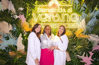 tres mujeres posan para una foto frente a un letrero de bienvenida al verano - 