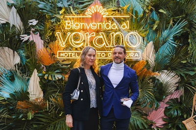 a man and woman pose in front of a sign that says bienvenido al verano - 