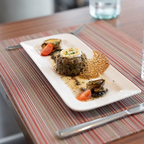 un plato de comida en una mesa con un cuchillo y un vaso de agua