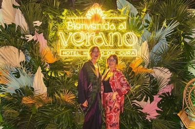 two women standing in front of a sign that says bienvenido al verano - 