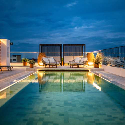 una piscina en la azotea de un edificio con muebles alrededor