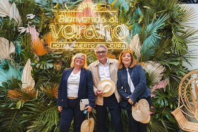three people pose in front of a sign that says bienvenido al verano - 