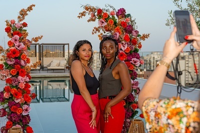 a woman is taking a picture of two women in front of flowers - 