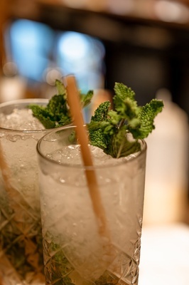 two glasses of iced drinks with mint leaves and straws - 