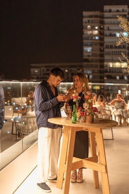 a man and a woman are standing at a table looking at their phones - 