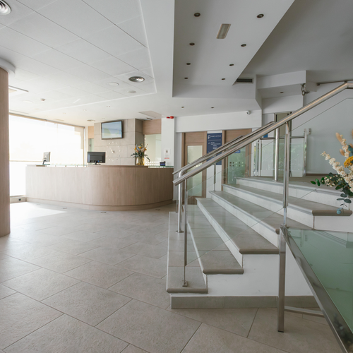 a reception area with stairs and a vase of flowers