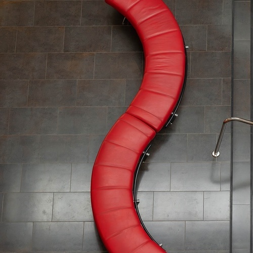 un banco curvo de cuero rojo sobre un suelo de baldosas