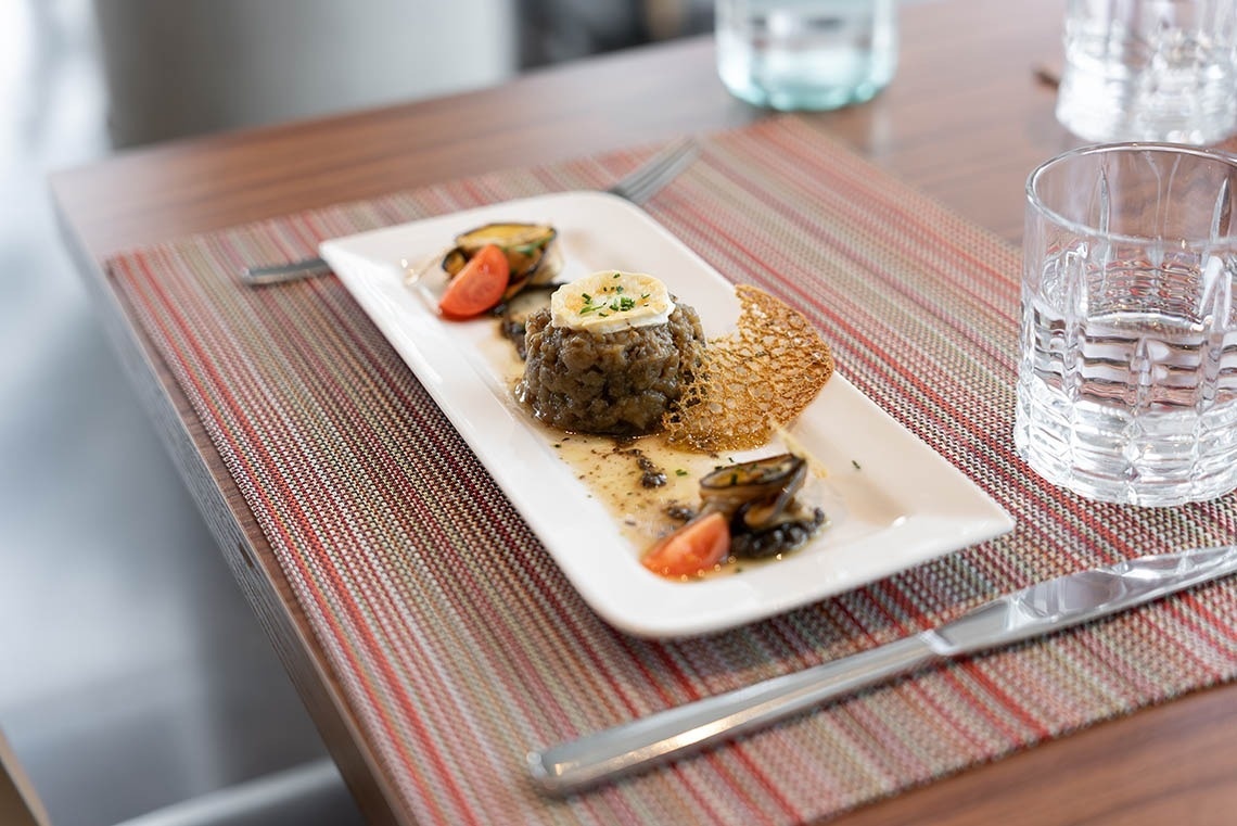 un plato de comida en una mesa con un cuchillo y un vaso de agua