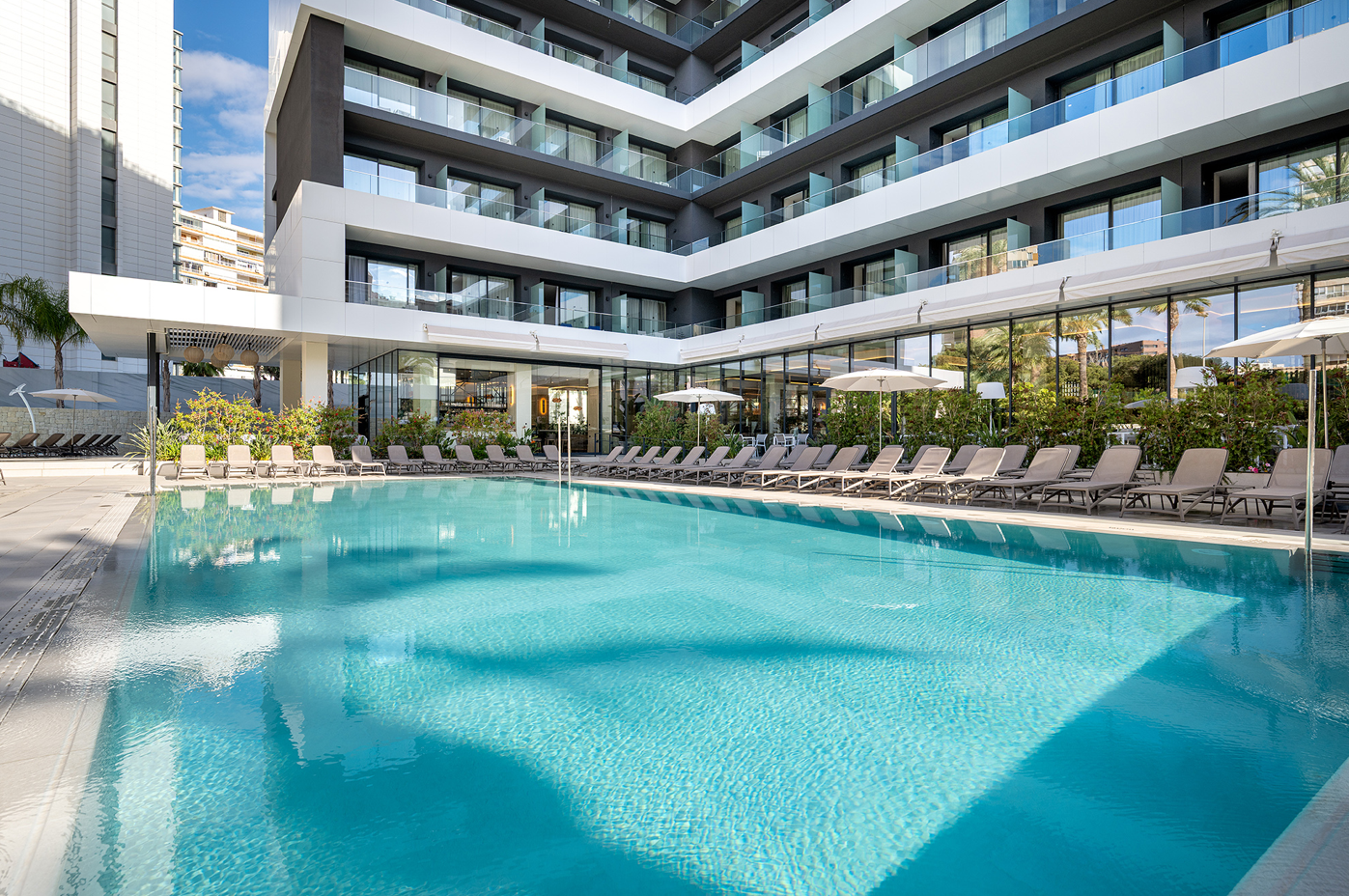 una piscina rodeada de sillas y sombrillas en un hotel