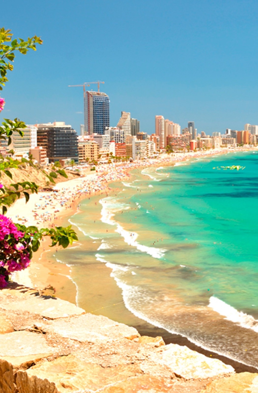 Playa vibrante con mar turquesa, ciudad costera y hoteles. Ideal para unas vacaciones de sol y playa.