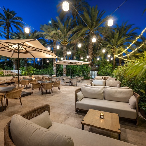 a patio area with tables chairs and umbrellas at night