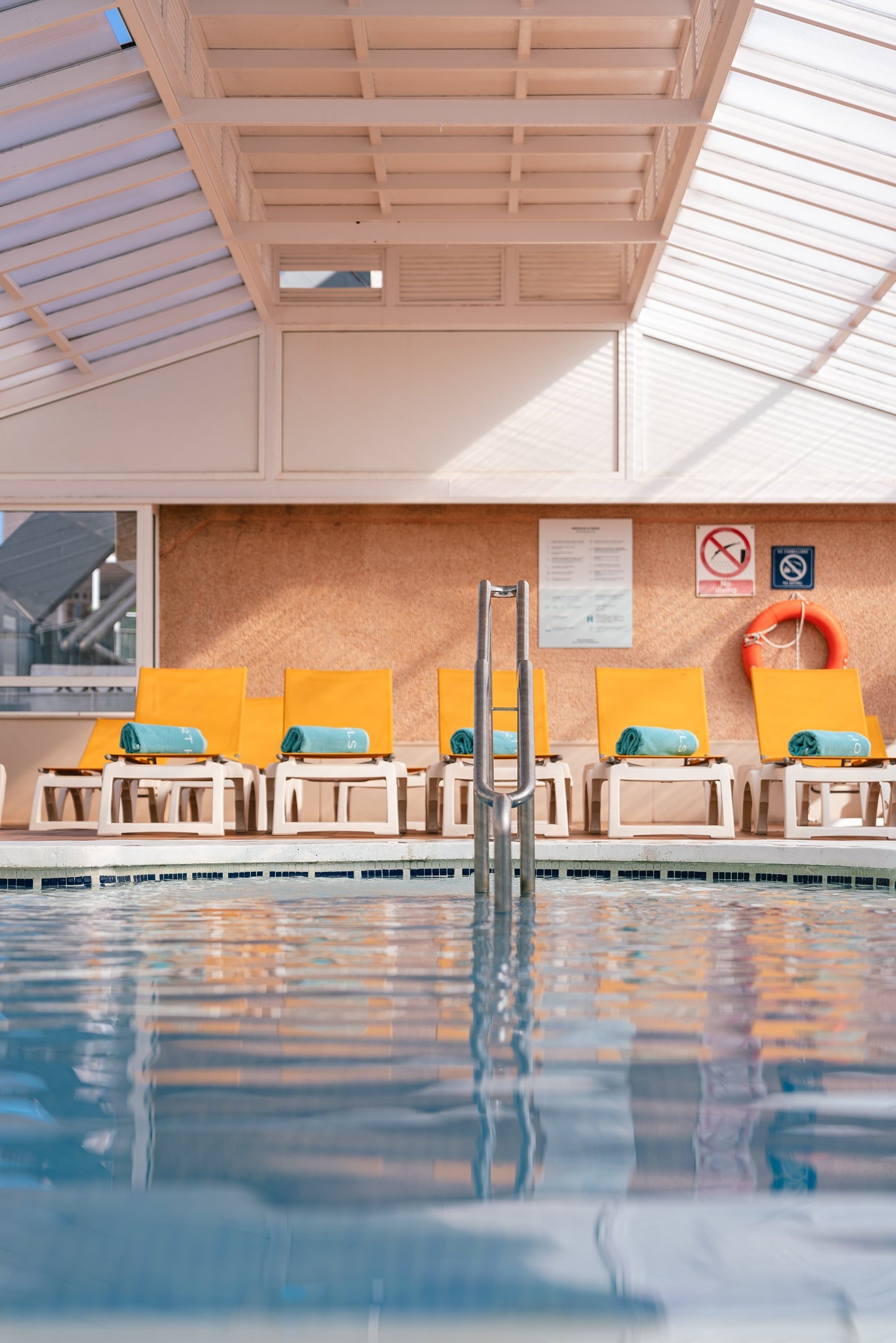 una piscina cubierta con sillas amarillas y una señal que dice no fumar