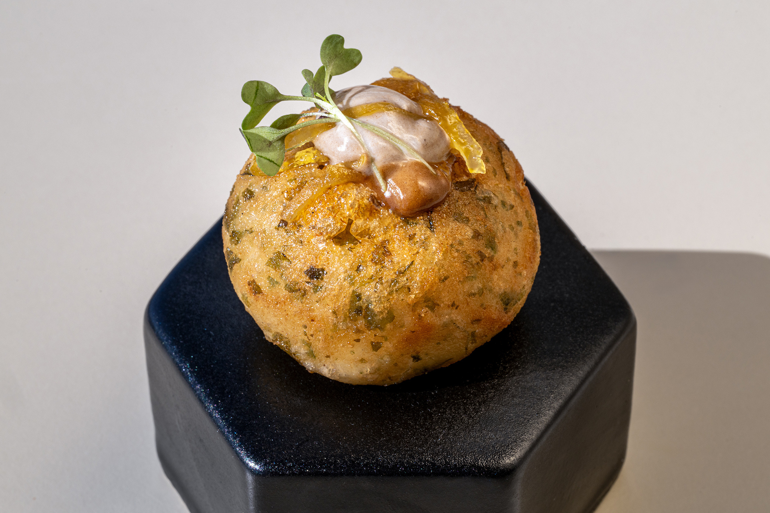 Arancini con hierbas, glaseado y brotes en base negra. Port Hotels: Corporativa