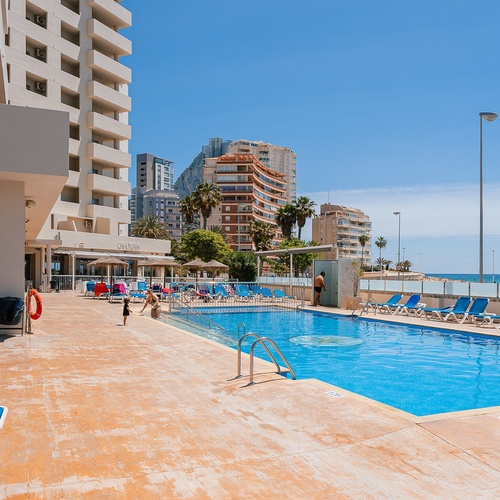 a large swimming pool with a hotel in the background