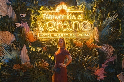 a woman stands in front of a sign that says hotel huerto del cura - 