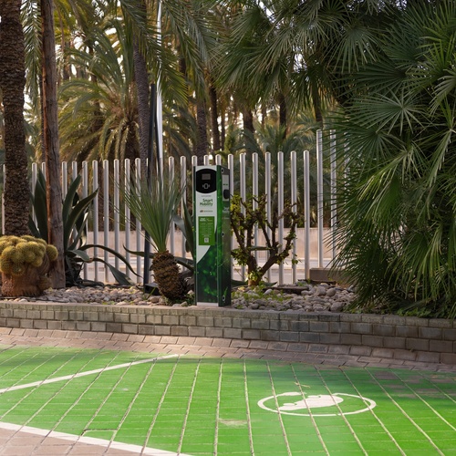 a green charging station in front of a hotel