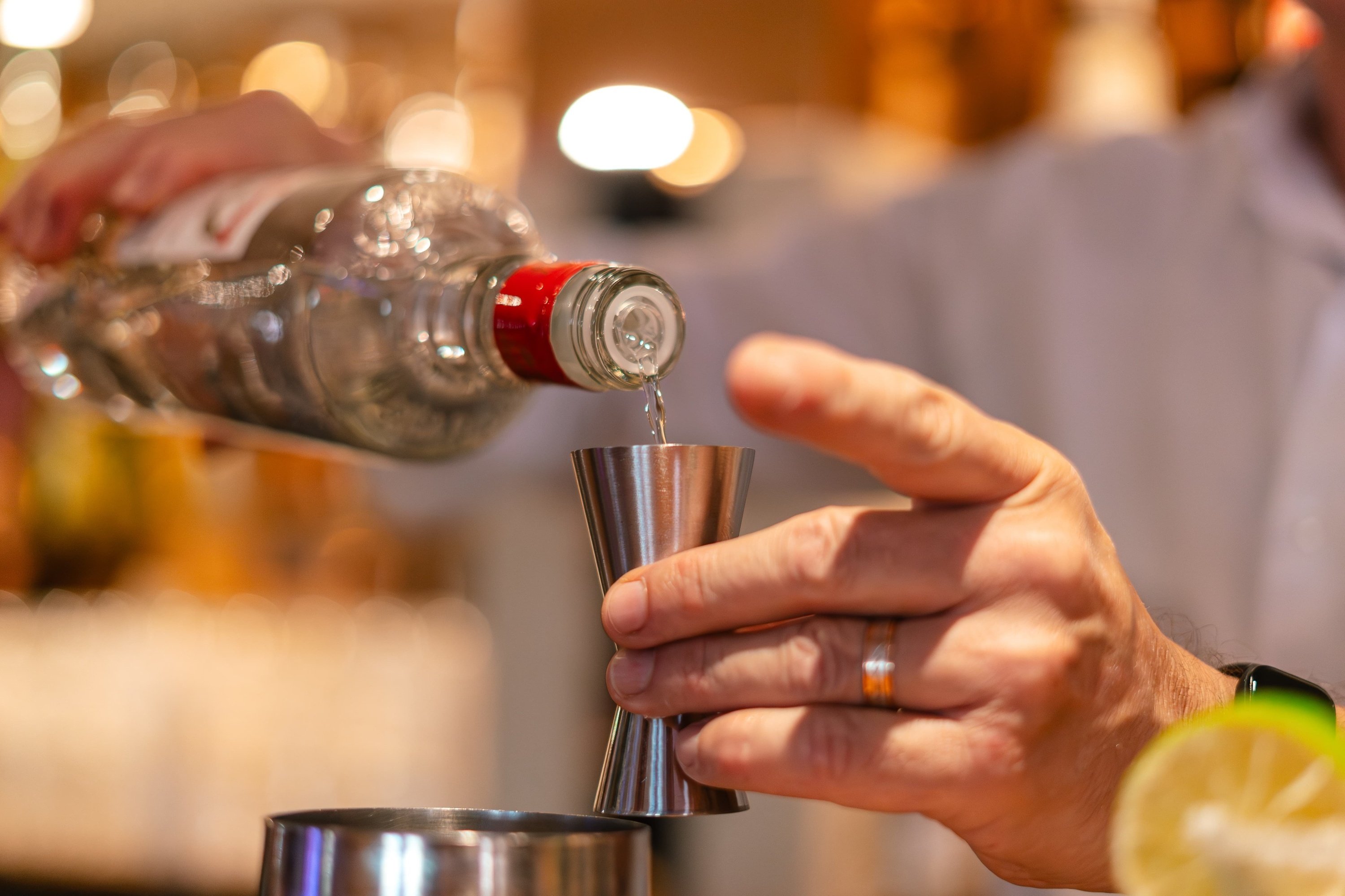 a bottle of vodka is being poured into a measuring cup