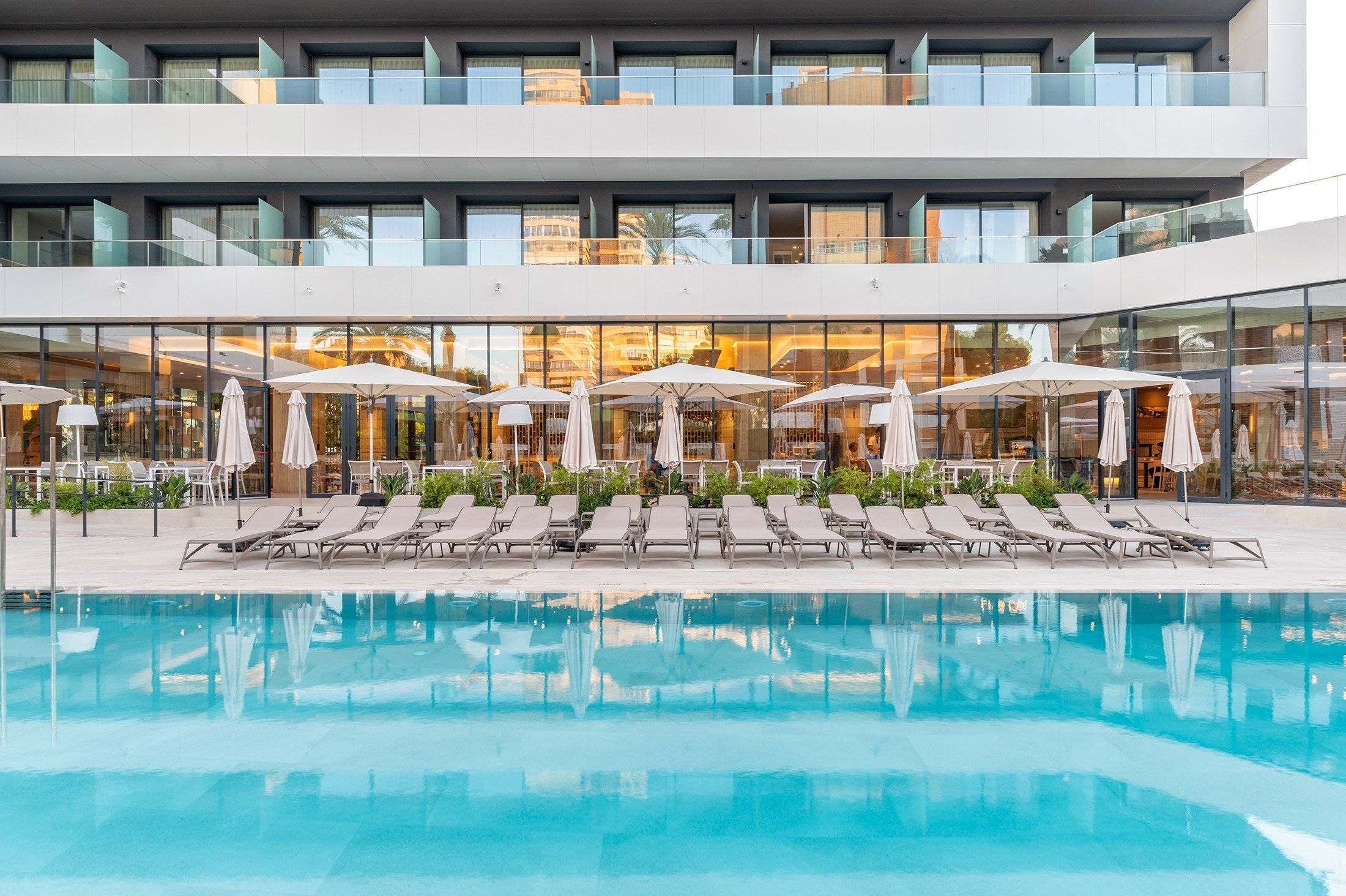 una piscina rodeada de sillas y sombrillas en un hotel