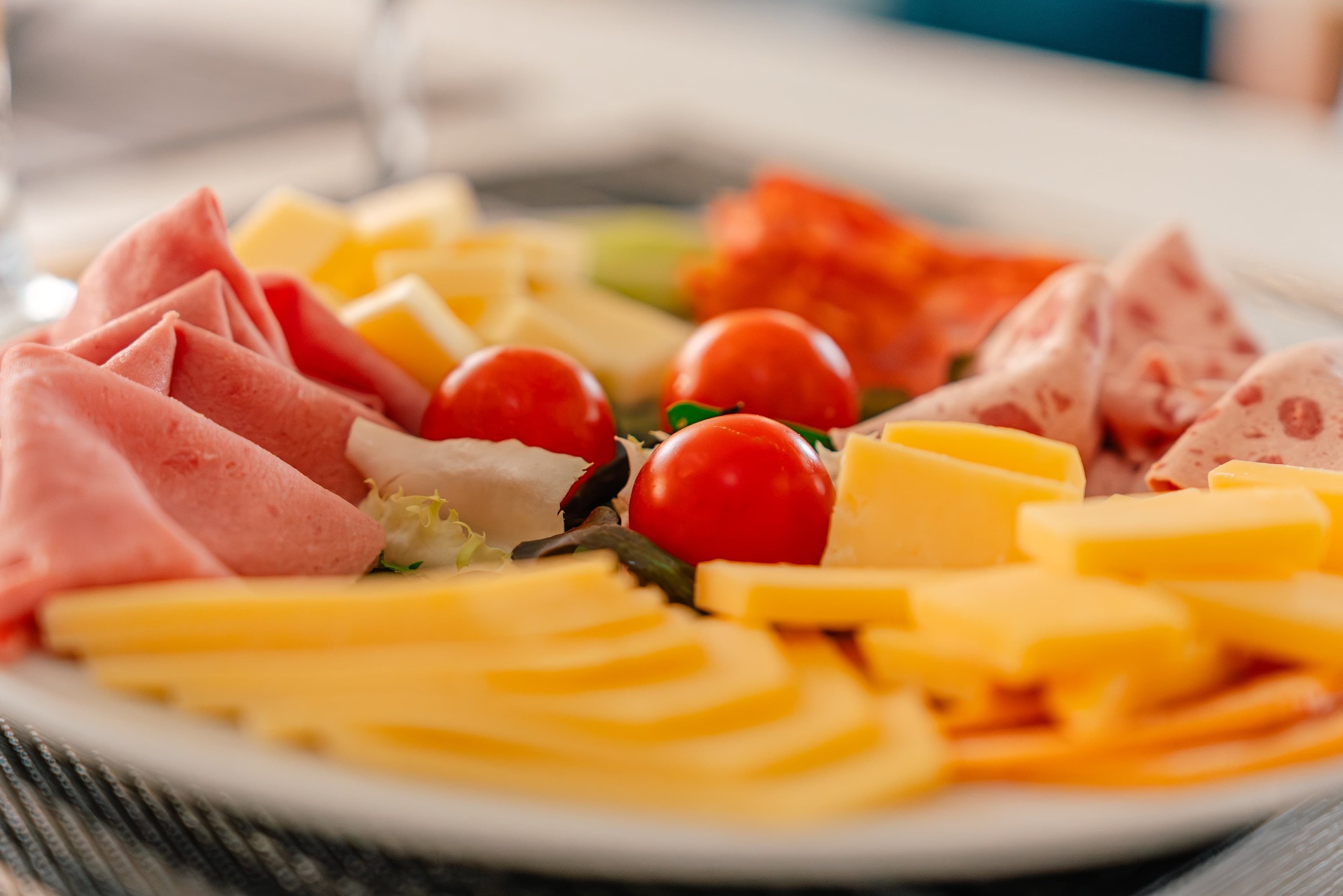 un plato blanco lleno de queso tomates y jamón