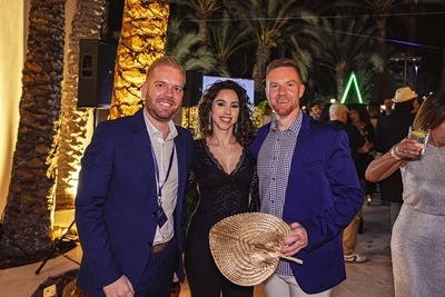 a man in a blue jacket holds a fan next to two other people - 