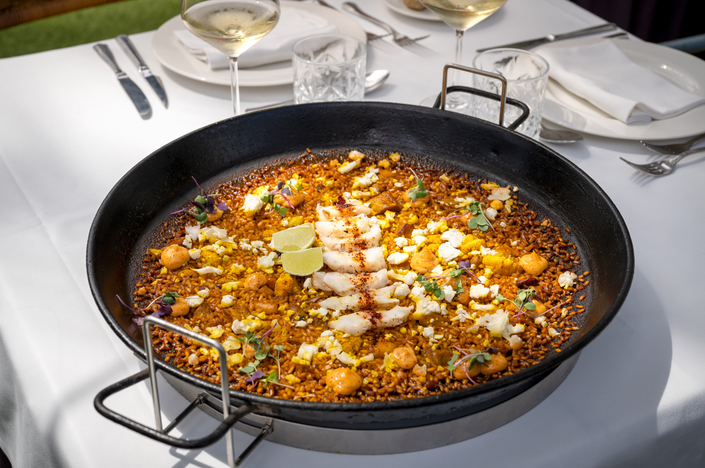 Exquisite seafood paella served in a large pan at our hotel's elegant restaurant dining table.