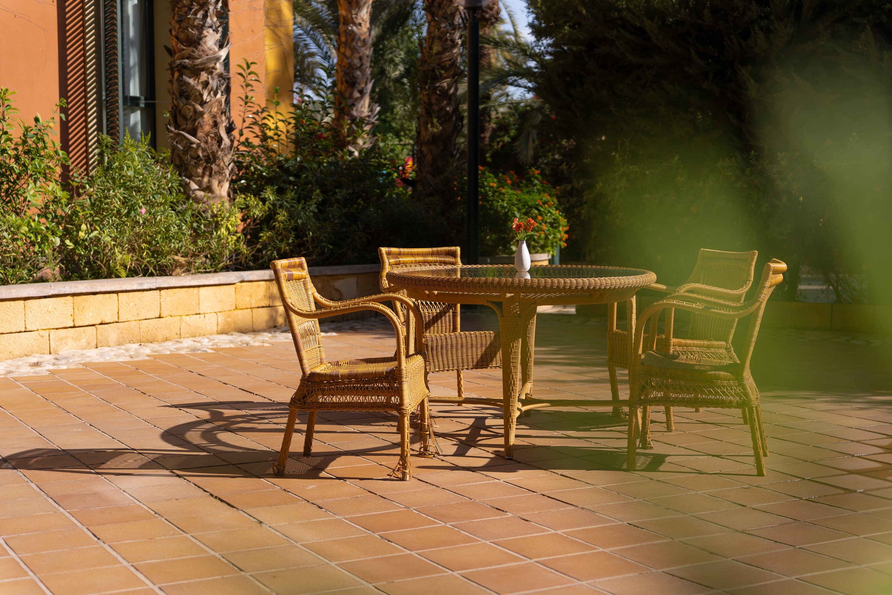 a table and chairs on a tiled patio with palm trees in the background