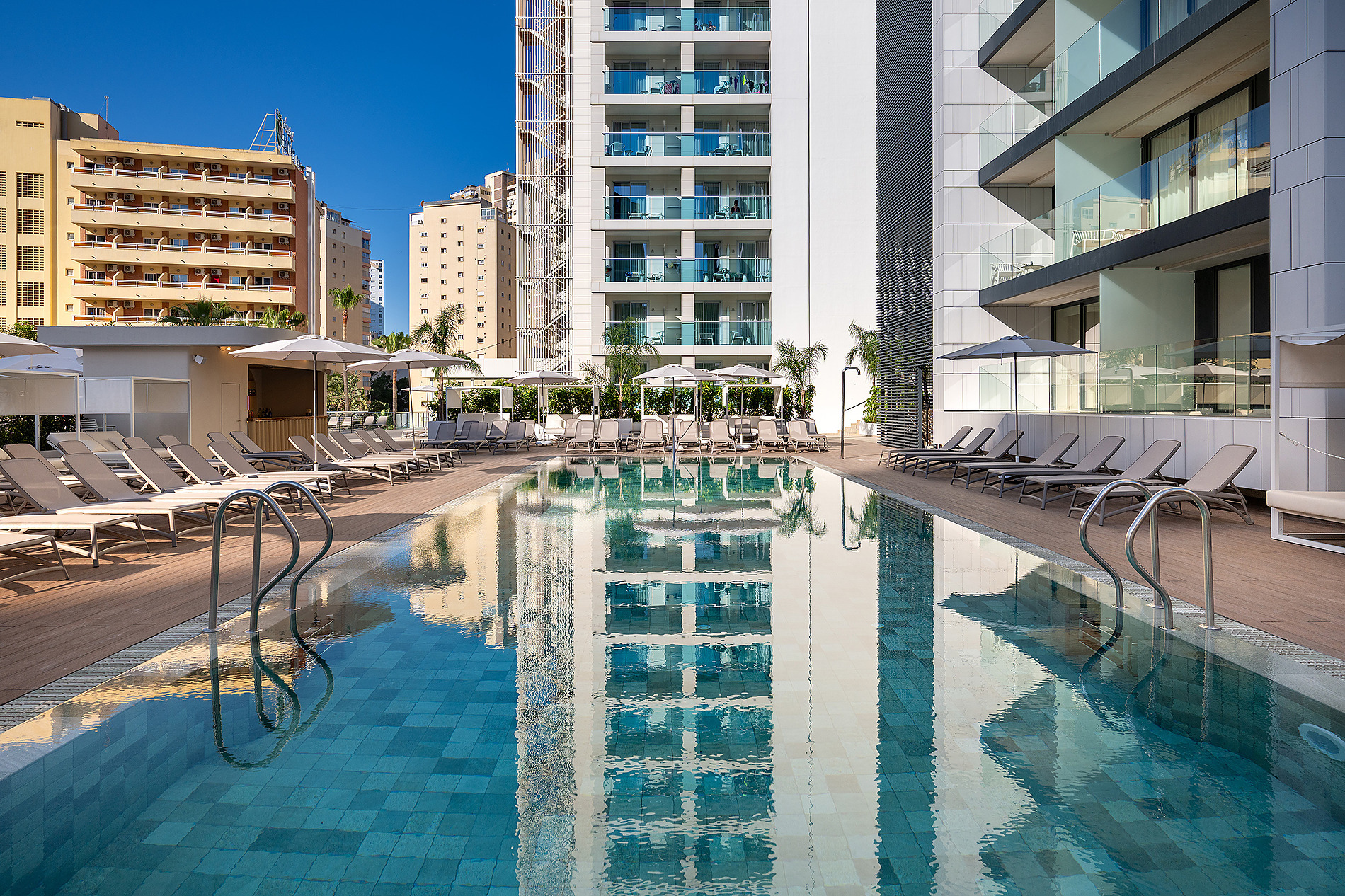 Piscina de hotel moderna con tumbonas y edificios circundantes Port Benidorm Hotel & Spa | Alicante | Port Hotels | Web oficial