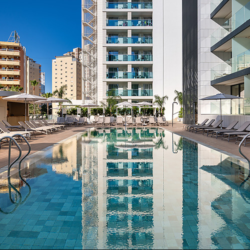 Piscina y tumbonas con vista a los edificios modernos, ideal para Port Hotels: Corporativa.