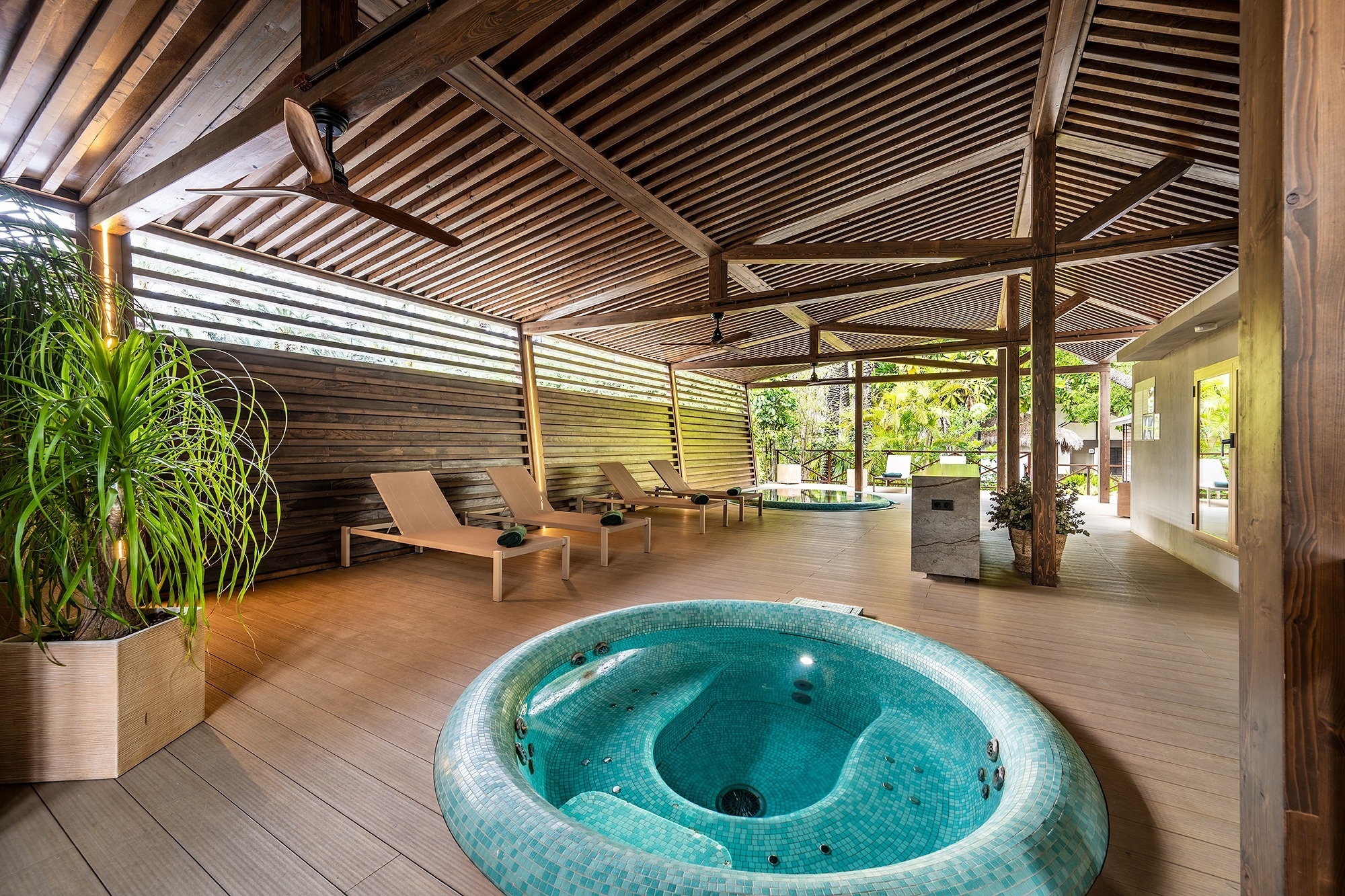 a hot tub is surrounded by lounge chairs under a wooden roof